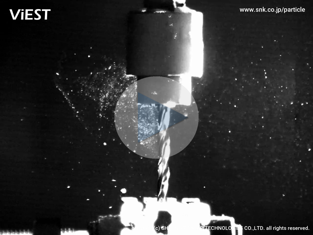 <big><big><b>明るい加工室で、ボール盤でアルミ材に穴をあけるときの粉塵です。穿孔で発生する粉塵をハイスピードカメラで撮影しました。飛び散っている比較的大きな切粉と、ドリル刃に沿って上昇する微粒子の様子が分かります。<big><b>
